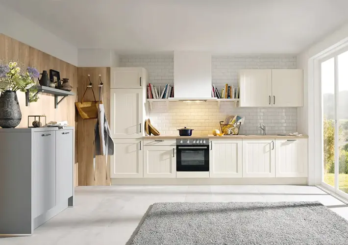 Weiße Küche mit Holzfront, Backofen, Spüle, Regalen und grauem Teppich